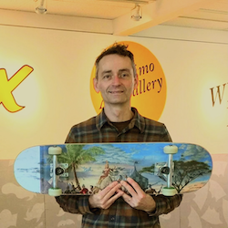 Kim holding Kent Monkman painted skateboard